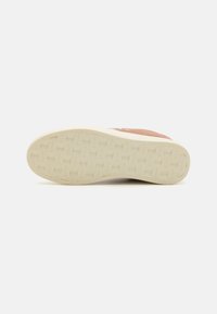 Sulla suola della sneaker, un materiale gommoso texturizzato di colore bianco sporco. Presenta un design di grip pattern e una parte superiore in tela rosa.