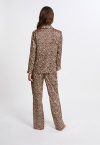 Ensemble de pyjama à imprimé léopard en beige et marron. Chemise à manches longues avec col et pantalon assorti à coupe ample. Texture de tissu douce.