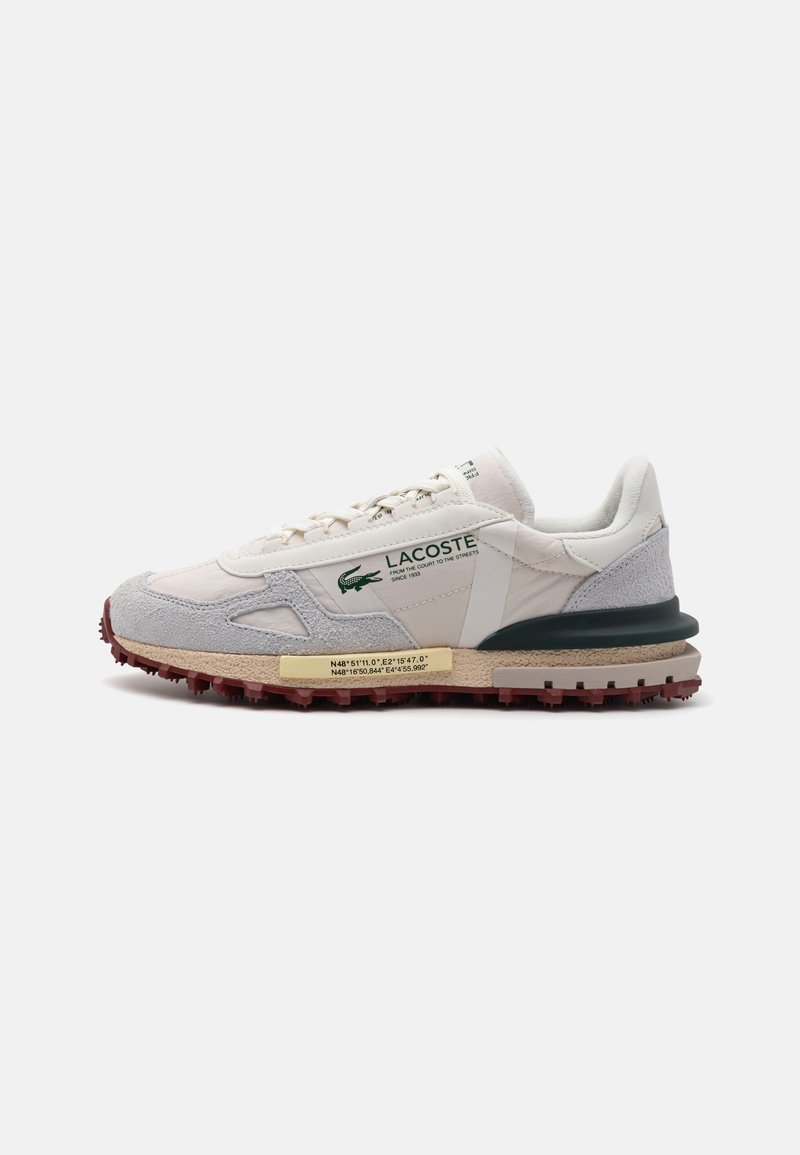 Lacoste sneakers med en kombinasjon av hvitt skinn og grå semsket skinn, snøredesign, teksturert gummisåle og grønne logo accenter.