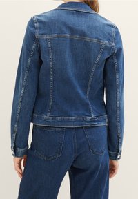 Jeansjacka med en klassisk design i mörkblått, med en skräddarsydd passform, sömnadsdetaljer och knapppryttningar vid ärmsluten.