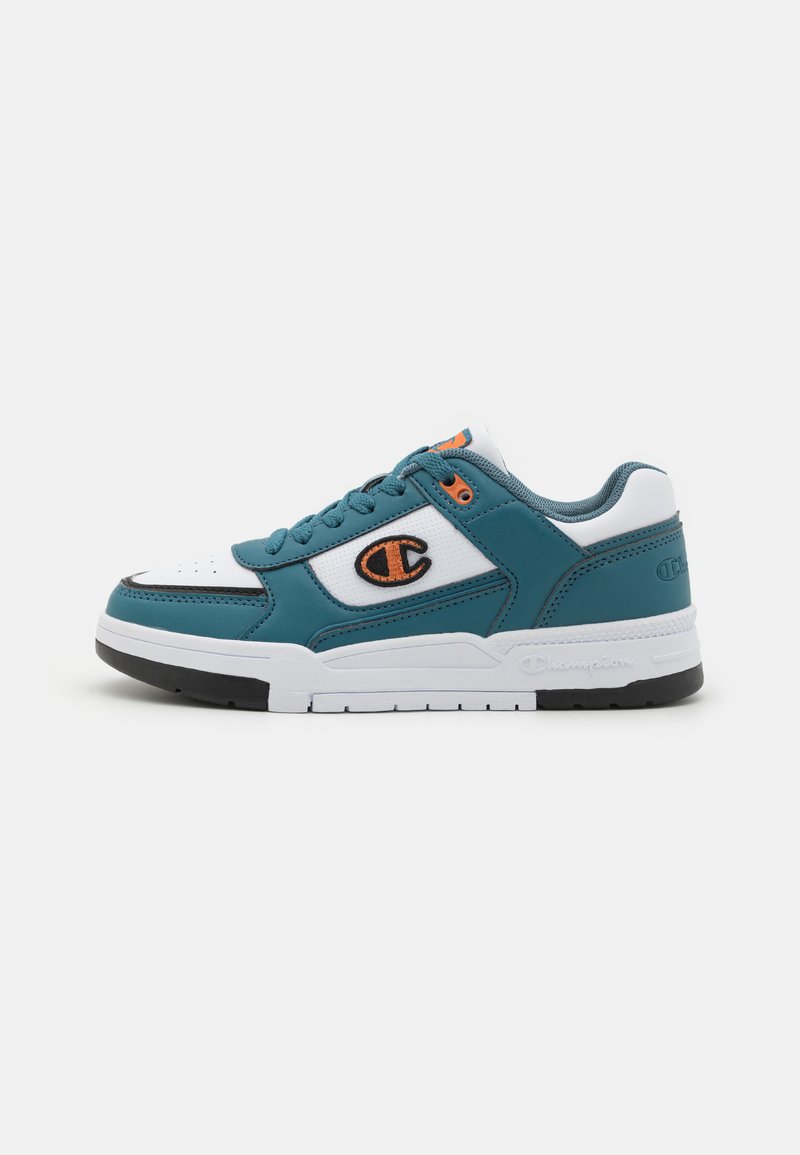 Sneaker teal e bianca con tomaia in pelle e rete, punta rotonda, lacci piatti e un accento arancione del logo sul lato. Suola in gomma nera.