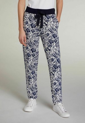Pantalons légers à motif floral bleu marine et blanc, avec une taille élastique à cordon et des poches latérales, associés à des baskets blanches.