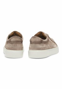 Sneaker in suede di un taupe chiaro con una finitura liscia. Suola in gomma bianca, design minimalista e piccolo dettaglio di branding sul tallone.
