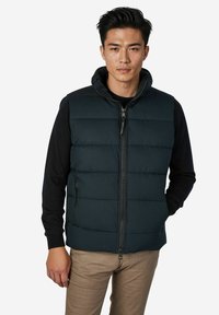 Gepolsterte Weste in Dunkelmarine mit hohem Kragen und durchgehendem Reißverschluss. Verfügt über zwei Seitentaschen und eine Kapuze, ergänzt durch ein schwarzes Langarmshirt.