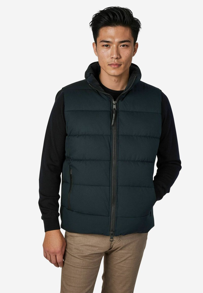 Gepolsterte Weste in Dunkelmarine mit hohem Kragen und durchgehendem Reißverschluss. Verfügt über zwei Seitentaschen und eine Kapuze, ergänzt durch ein schwarzes Langarmshirt.