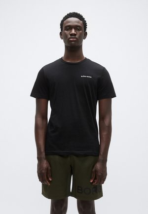 T-shirt noir à manches courtes avec un col rond et le logo blanc "BJÖRN BORG" sur la poitrine gauche, associé à un short vert olive avec une typographie audacieuse.