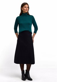 Türkiser Rollkragenpullover mit langen Ärmeln, kombiniert mit einem schwarzen Midi-Rock und schwarzen Stiefeletten. Glatte Texturen und einfaches Design.