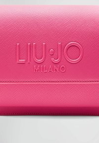 Lyserød tekstureret pung med prægning af "LIU·JO MILANO" logo, der har en glat overflade og synlige syninger. Kompakt rektangulær form.