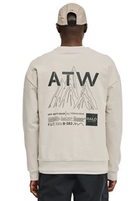 Beżowy sweatshirt z grafiką górską, logo "ATW" oraz nadrukowanymi metkami. Ribbed cuffs and hem, design z okrągłym dekoltem.