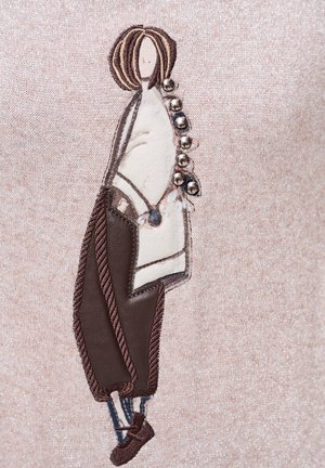 Geborduurde stof met een gestileerde figuur met bruin haar, gekleed in een witte top en bruine broek met decoratieve knopen en accenten.