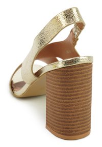 Gouden metallic sandaal met bandjes en een gestructureerde bruine blokhak. Soepel interieur, open teen ontwerp en verstelbare achterband.