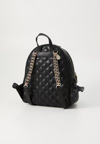 Sac à dos en simili cuir noir matelassé avec des accents en chaîne argentée, bretelles doubles et une poignée supérieure, doté d'une fermeture éclair.