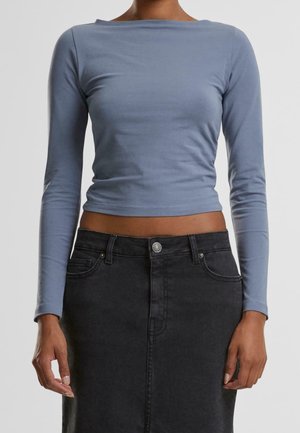Lichtblauwe long-sleeve top met een bootneck en een getailleerd ontwerp, gecombineerd met een hoge taille zwarte denimrok met een knoopsluiting aan de voorkant.
