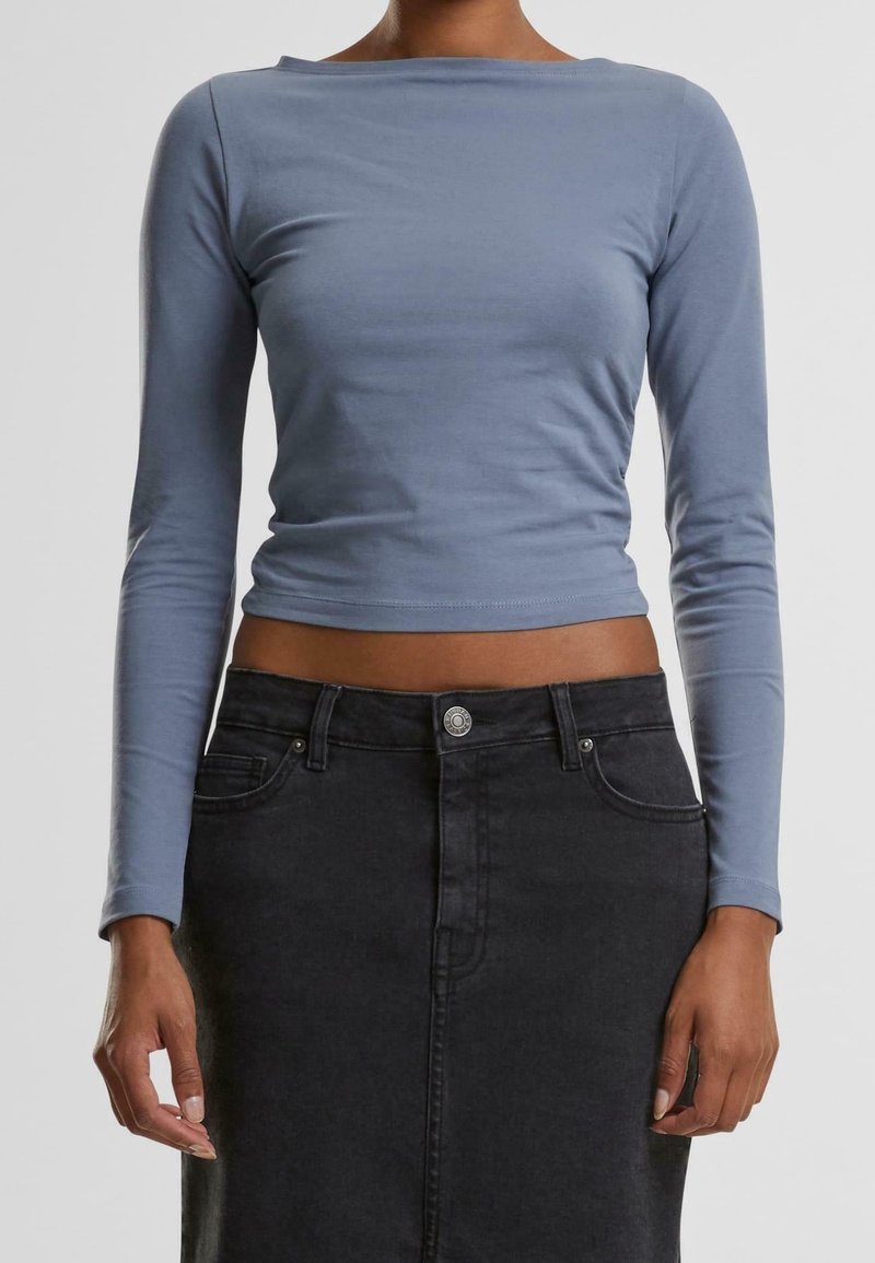 Light blue long-sleeve top with a boat neckline and fitted design, paired with a high-waisted black denim skirt featuring a front button closure.