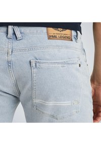 Hellblaue Jeans aus Denim mit einem Leder-PME-Legend-Label auf der Rückseite, ausgestattet mit Gesäßtaschen und dezenten Nähdetails.