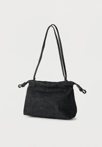 Μαύρη τσάντα ώμου από τζιν με κλείσιμο με κορδόνι και λεπτά διπλά λουριά που κρέμονται μπροστά σε απλό λευκό φόντο.