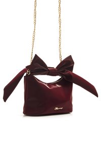 Borsa a mano in pelle patent bordeaux con tracolla in catena dorata e grande fiocco decorativo sulla parte superiore. Chiusura con zip e dettaglio del logo in tonalità dorata sul davanti.