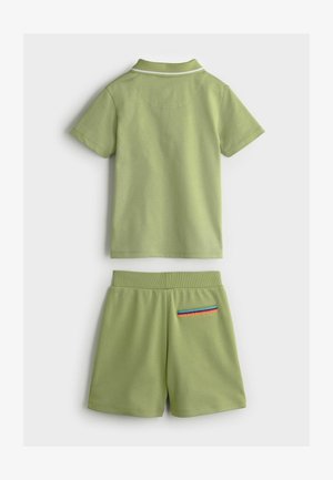 Grünes Baumwoll-Zweiteiler-Set mit einem kurzärmeligen Poloshirt mit weißem Kragen und passenden Shorts mit gestreiftem Taschenakzent.