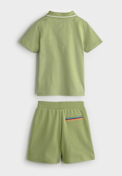Grünes Baumwoll-Zweiteiler-Set mit einem kurzärmeligen Poloshirt mit weißem Kragen und passenden Shorts mit gestreiftem Taschenakzent.