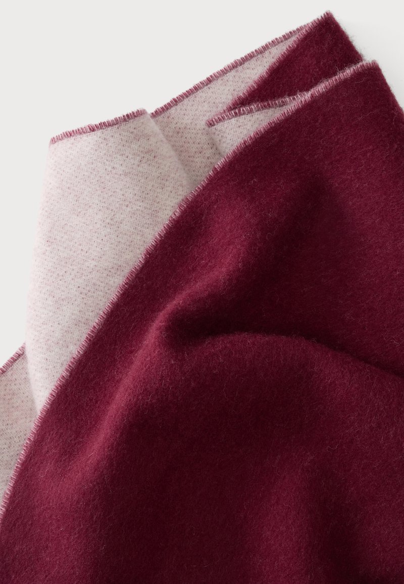 Soft woolen fabric folded to show dark red and light grey sides with neatly stitched edges.