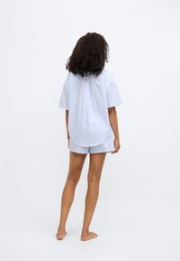 Ριγέ μπλε και λευκό πουκάμισο με κοντά μανίκια και αντίστοιχα σορτς, με άνετη εφαρμογή και απαλό ύφασμα, πιο πίσω όψη.