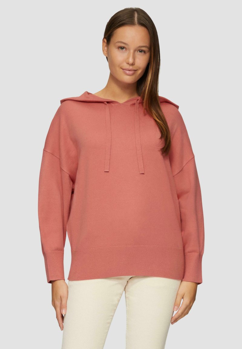 Różowa bluza z kapturem w miękkim materiale, o luźnym kroju, z ściągaczami na mankietach i u dołu. Z przodu z wiązaniami przy dekolcie.