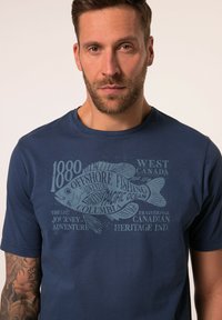 Námořnické modré bavlněné tričko s grafickým potiskem ryby a textovými prvky, kulatým výstřihem, krátkým rukávem a hladkou strukturou.