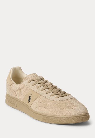 Μπεζ σουέτ low-top αθλητικό παπούτσι με ομοιόχρωμους κορδόνια, λαστιχένια σόλα και μαύρο λογότυπο Polo Ralph Lauren στο πλαϊνό πάνελ.