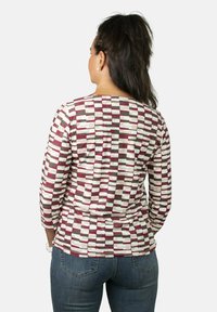 Camisa de manga larga con un diseño de múltiples patrones que presenta bloques en tonos burdeos, rosa y gris. Fabricada con un material suave y con un cuello redondo.