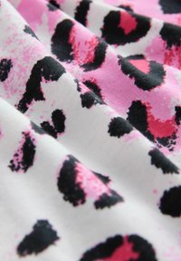 Leopardprintstof met grote zwarte en roze vlekken op een witte achtergrond, met een zachte textuur en een soepele val.