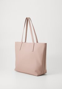 Sac fourre-tout rose avec une texture lisse et mate, de forme rectangulaire et deux longues anses. Présente un design minimaliste, sans matériel visible.