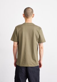 T-shirt en coton olive avec col rond, manches courtes et coupe décontractée, montrant la vue de dos. Texture lisse, sans motifs visibles.