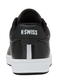 Mustat nahkakengät, joissa on valkoisia yksityiskohtia ja pinnassa rakenne. Varressa pehmuste ja takaosassa logo. Kumiulkopohja.