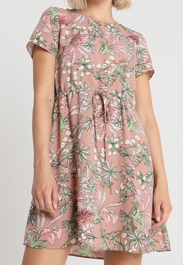 Vestido de manga corta floral en rosa con patrones botánicos en verde y blanco. Cuenta con una cintura con cordón y una tela suave y ligera.