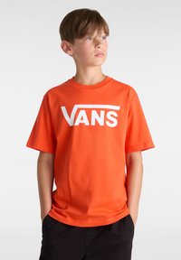Oranžové bavlněné tričko s výrazným bílým logem "VANS". Krátké rukávy, kulatý výstřih a hladká textura.