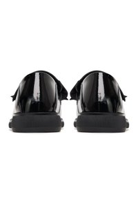 Black patent leather shoes with a shiny finish, a rounded shape, and flat black rubber soles, featuring a decorative bow accent on the heel.