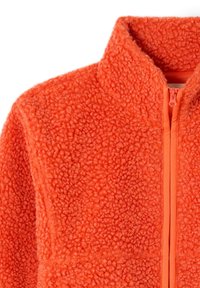 Jasnopomarańczowa kurtka z polaru sherpa z pełnym zamkiem błyskawicznym z przodu i stojącym kołnierzem, prezentująca miękki, teksturowany materiał.