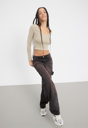 Casual outfit featuring a fitted beige long-sleeve top and dark wide-leg pants, paired with chunky white sneakers. Smooth textures and subtle details.