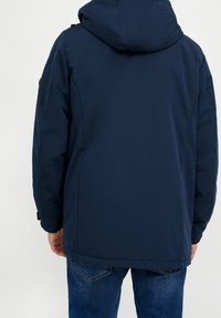 Tmavě modrý dlouhý kabát s kapucí, vyrobený z hladké látky. Má volný střih, elastické manžety a rovný lem.