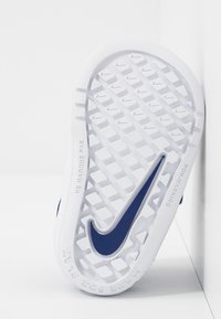 Biała gumowa podeszwa z teksturowanym wzorem oraz niebieskim logo Nike. Posiada konstrukcję niewidzącą i grawerowany napis z boku.