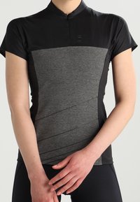 Černý a šedý cyklistický dres s krátkými rukávy, vysokým límcem, texturovanou tkaninou a diagonálním vzorem na přední straně. Přiléhavý střih.
