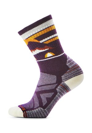 Fioletowa skarpetka z pomarańczowym, białym i żółtym wzorem przedstawiającym zachód słońca i góry, z amortyzowaną piętą i palcem oraz ściągaczem, na białym tle.