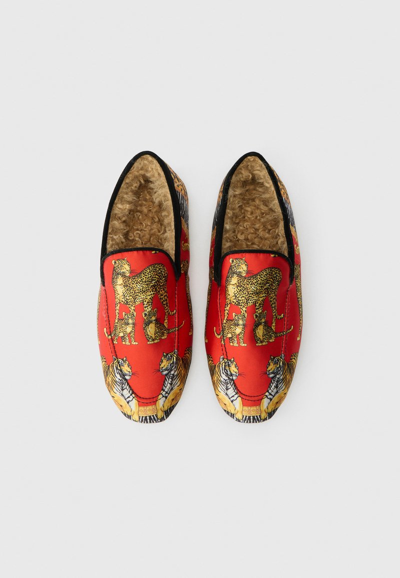 Rote Slipper mit einem flauschigen Material, das Leoparden- und Tiger-Muster aufweist. Schwarze Akzente umrahmen die Öffnungen.