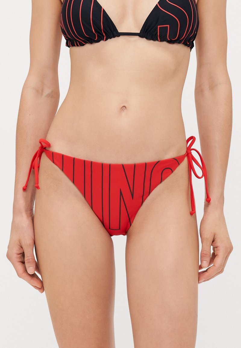 Červené bikiny s širokými čiernymi pruhmi, s bočnými viazaniami pre nastaviteľné prispôsobenie. Hladká tkanina s elegantným strihom.