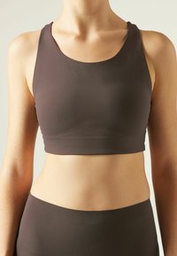 Brun sport-bh i mjukt, stretchigt material med rundad halsringning och sömlös design, i kombination med matchande högmidjade trosor.