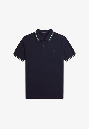 Mørkeblå polo-shirt lavet af bomuld, med en to-knaps placket, grønne og hvide striber på kraven og ærmerne, samt et broderet logo.