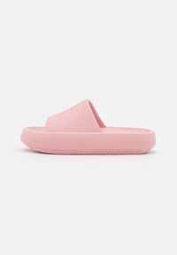 Sandale rose à enfiler avec un dessus texturé et une semelle lisse. Forme arrondie avec un profil bas, fabriquée en un matériau semblable à du caoutchouc avec des rainures subtiles.