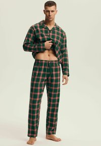 Zielony zestaw piżam w kratę, składający się z rozpinanej koszuli z długimi rękawami i spodni z elastycznym pasem. Czerwona i biała krata o miękkiej teksturze.
