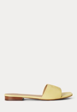 Κίτρινο δερμάτινο σανδάλι τύπου slide με επίπεδη ξύλινη σόλα και φαρδιά μπροστινή λωρίδα σε λευκό φόντο.