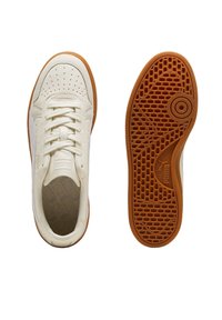 Sneakers in pelle crema con punta perforata, dettagli bianchi, lacci piatti e suola in gomma con un motivo di grip texturizzato.
